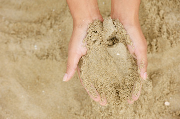 Two hands holding grains of sand