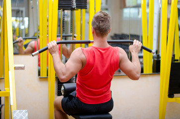 Handsome young man working out on gym equipment