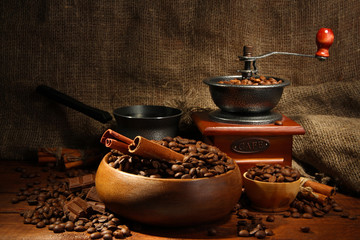 Coffee grinder, turk and cup of coffee on burlap background