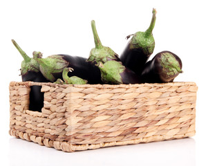 Fresh eggplants in wicker basket isolated on white