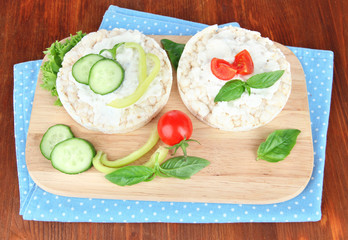 Tasty crispbreads with vegetables on wooden background