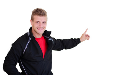 Smiling, young personal trainer pointing finger at blank space