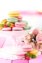 Gentle macaroons in vase on table on light background
