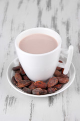 Cocoa drink and cocoa beans on wooden background