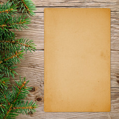 Christmas tree branches and old paper on wooden background