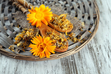 Fresh and dried calendula flowers on wooden background