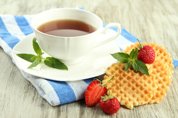 Cup of tea with cookies and strawberries on table close-up