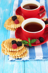 Cups of tea with cookies and berries on table close-up