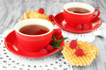 Cups of tea with cookies and raspberries on table close-up
