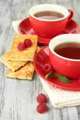 Cups of tea with cookies and raspberries on table close-up