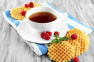 Cup of tea with cookies and raspberries on table close-up