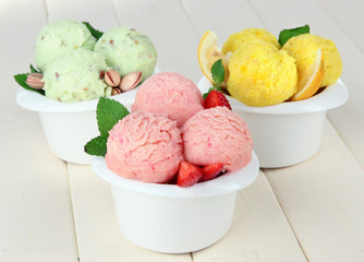 Tasty ice cream scoops in bowls, on wooden table