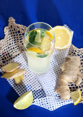 Glass of cold tea with ginger on napkin on blue table