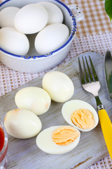 Boiled eggs on wooden board on tablecloth