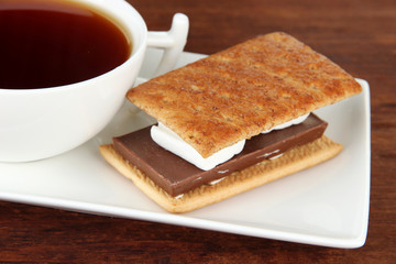Fototapeta na wymiar Sweet sandwich with cup of tea on wooden background
