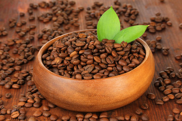 Coffee beans in bowl on wooden background