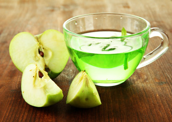 Transparent cup of green tea with apple on wooden background
