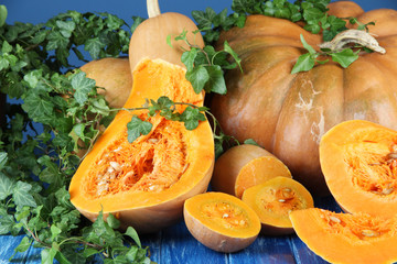 Ripe cut pumpkins on wooden table on blue background
