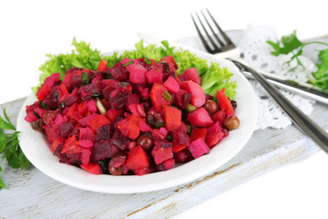 Beet salad on plate on napkin on wooden board isolated on white