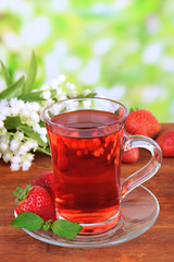 Delicious strawberry tea on table on bright background