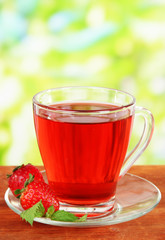 Delicious strawberry tea on table on bright background