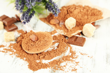 Cocoa powder in spoon on wooden table