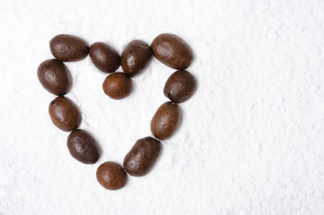 Heart of coffee beans on the background of powdered sugar