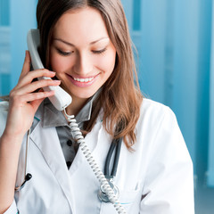 Young doctor on phone, at office