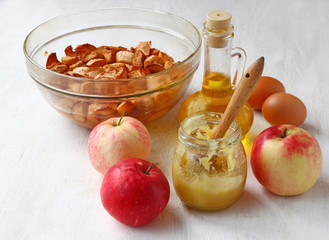 Fresh and baked apples, honey, eggs, oil on the kitchen table.