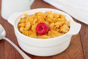 cornflakes with raspberry in white bowl