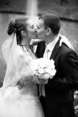 portrait of married couple kissing against fountain
