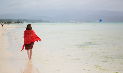 Fototapeta na wymiar Woman walking by white sand beach
