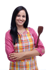 Young Indian woman holding kitchen utensil against white