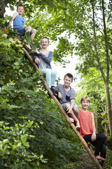 Naklejka na ściany i meble Four siblings sitting on a wooden ladder