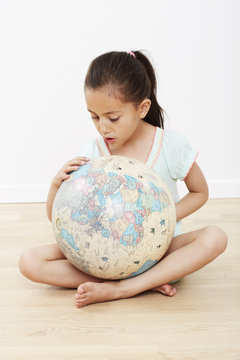 Young girl sitting on floor with globe