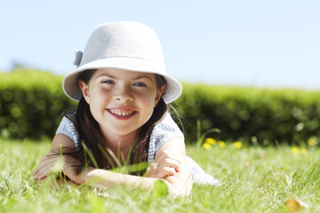 Young girl lying on grass smiling, portrait