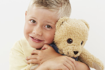 Young boy hugging teddy bear, portrait