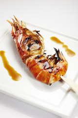 Jumbo shrimp on stick lying on a plate.