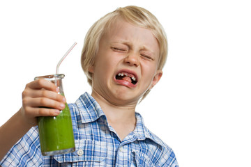 Boy pulling funny face holding green smoothie