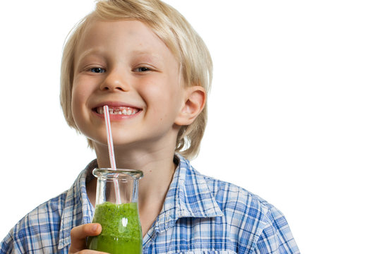Cute boy drinking green smoothie smiling