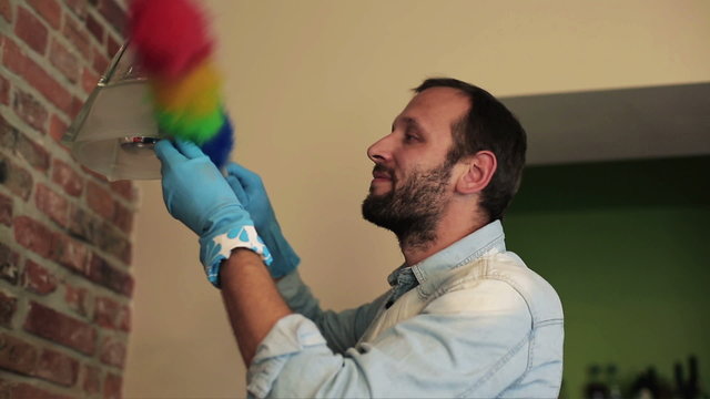 Man dusting the lamp and smiling to the camera