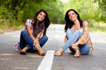 Mother and daughter sitting cross legged on the road