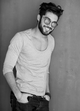 sexy fashion man with beard dressed casual smiling against wall