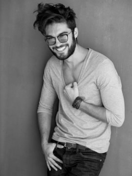 sexy man with beard dressed casual smiling against wall