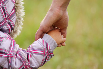 parent holds the hand of a small child