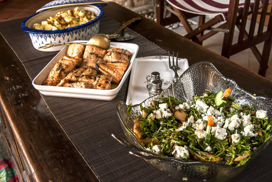 Rustic table with grilled salmon, salad and sauteed potatoes