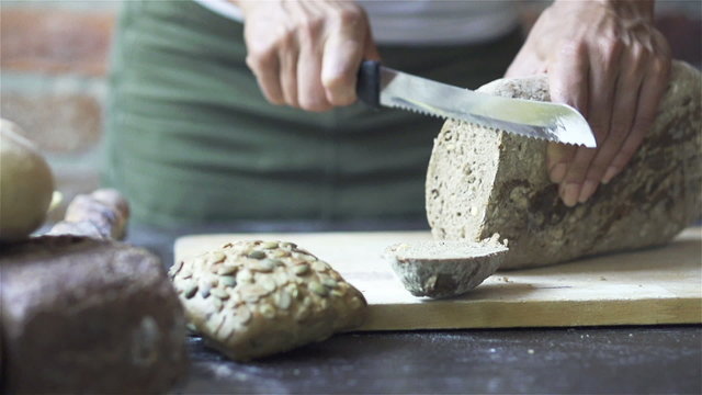 Woman cutting bread into slices, slow motion shot at 60fps