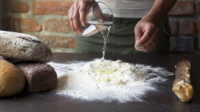 water adding to the dough by a woman, slow motion at 240 fps