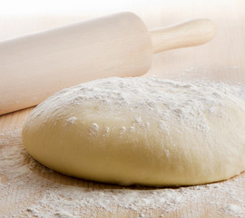 Dough with rolling pin on wooden table