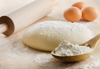 Dough with rolling pin on wooden table